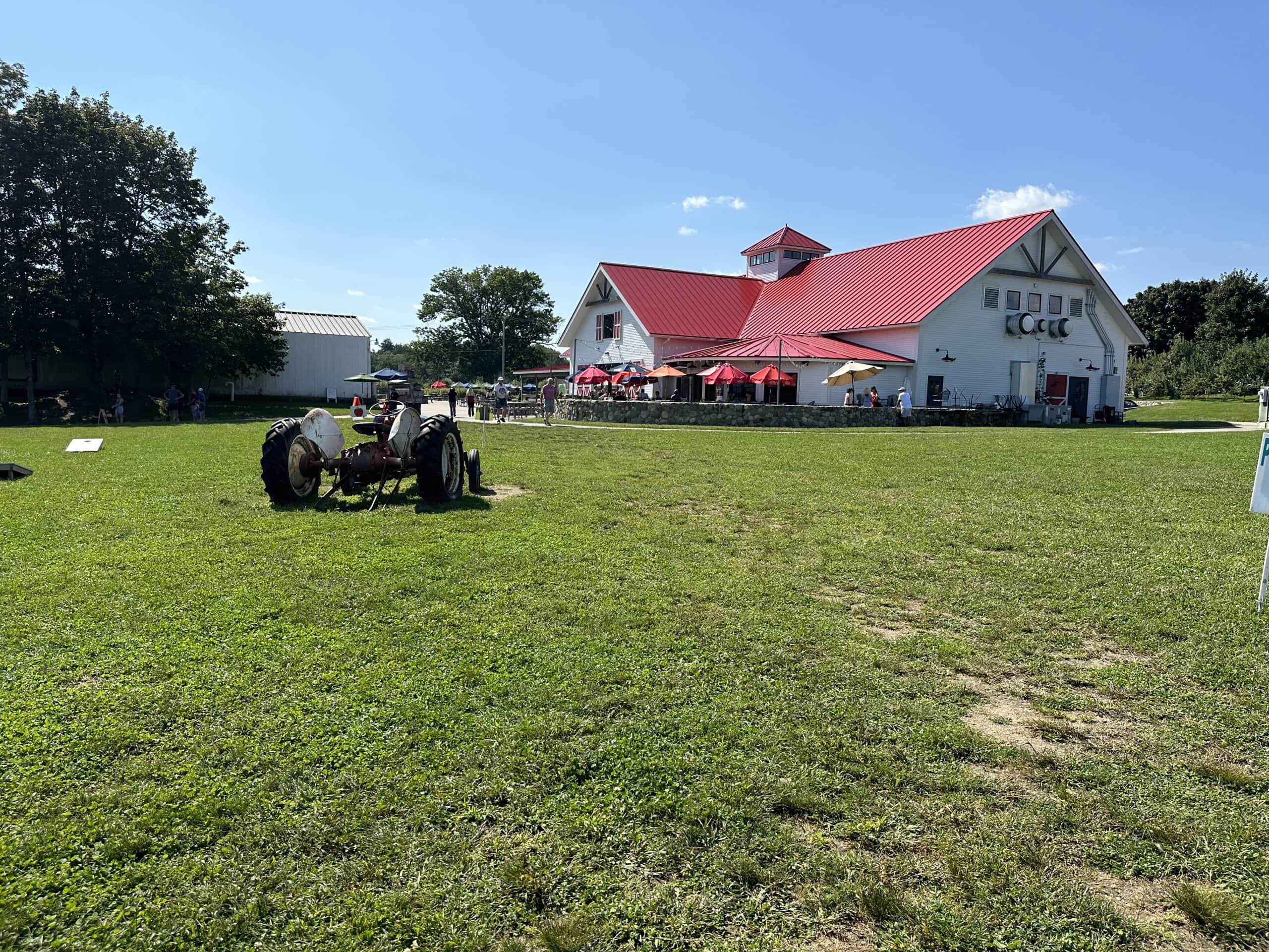 A giant barn sits in a green field underneath a blue sky